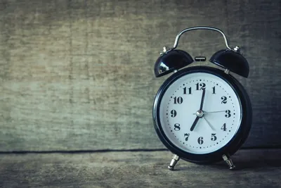 A black alarm clock sits alone on a table