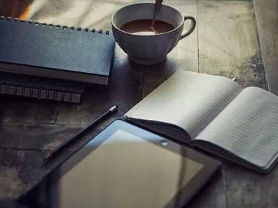 Tablet, coffee and journal sitting on table ready to use.